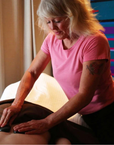 A Healing Waters massage therapist performing a hot stone massage on a client's back.