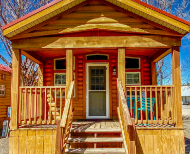 A cozy wood cabin at Healing Waters in Pagosa Springs Colorado, featuring a porch and a staircase leading to the front door.